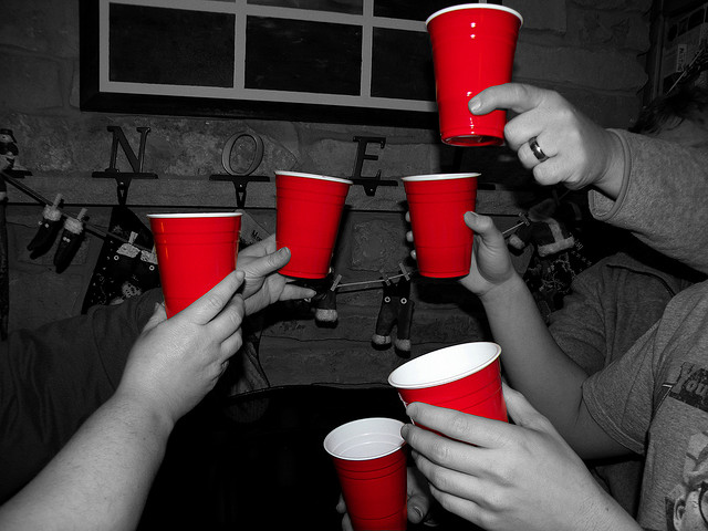 It's Not a Party selectively colored red plastic cups held up by partygoers