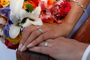 bride and groom's wedding rings on their hands with the bouquet