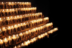 rack of lit candles in gold leaf holders