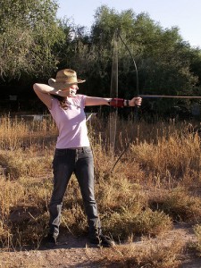 girl in pink shirt shooting a bow and arrow