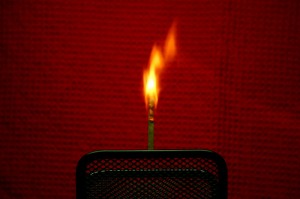 a match burning against a red background