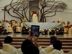 priest taking photo on iPad during liturgy